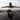 A motorcycle performing a stunt on a runway with a large airplane taking off in the background.