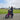 Father and child riding a pink AR Atom mini electric bicycle on a grassy park path.