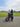 Father and child riding a pink AR Atom mini electric bicycle on a grassy park path.