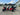 Red TrailMaster TBM X6 6-seater electric golf cart with 5kW lithium battery, foldable windshield, and aluminum rims in parking lot
