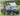 TrailMaster Taurus 50EV 4-seat electric golf cart in blue, featuring 60V motor, off-road tires, and LED headlights, on green grass.