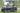 TrailMaster Taurus 50EV 4-seat electric golf cart on grass with DOT light package, aluminum wheels, and off-road tires