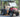 TrailMaster Taurus 50EV 4-seat electric golf cart with aluminum wheels, off-road tires, LED lights, and turn signals parked outdoors.
