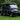 TrailMaster Taurus 80ED-GV 6-seat electric golf cart with an extended roof, shown on grass with a sleek black design.